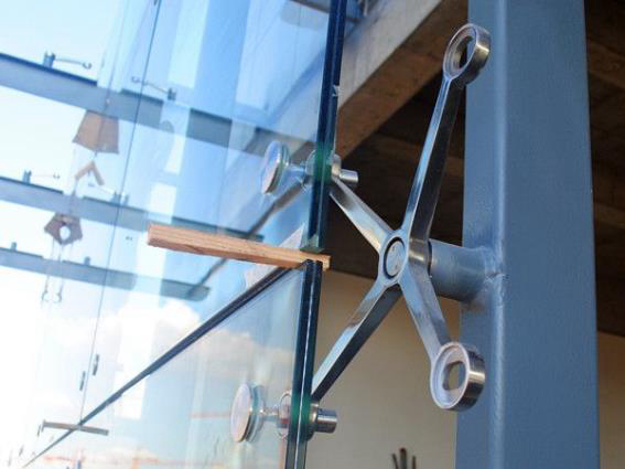 Vista detallada de la garra de araña de acero inoxidable utilizada para soportar la estructura de una gran pared de vidrio.